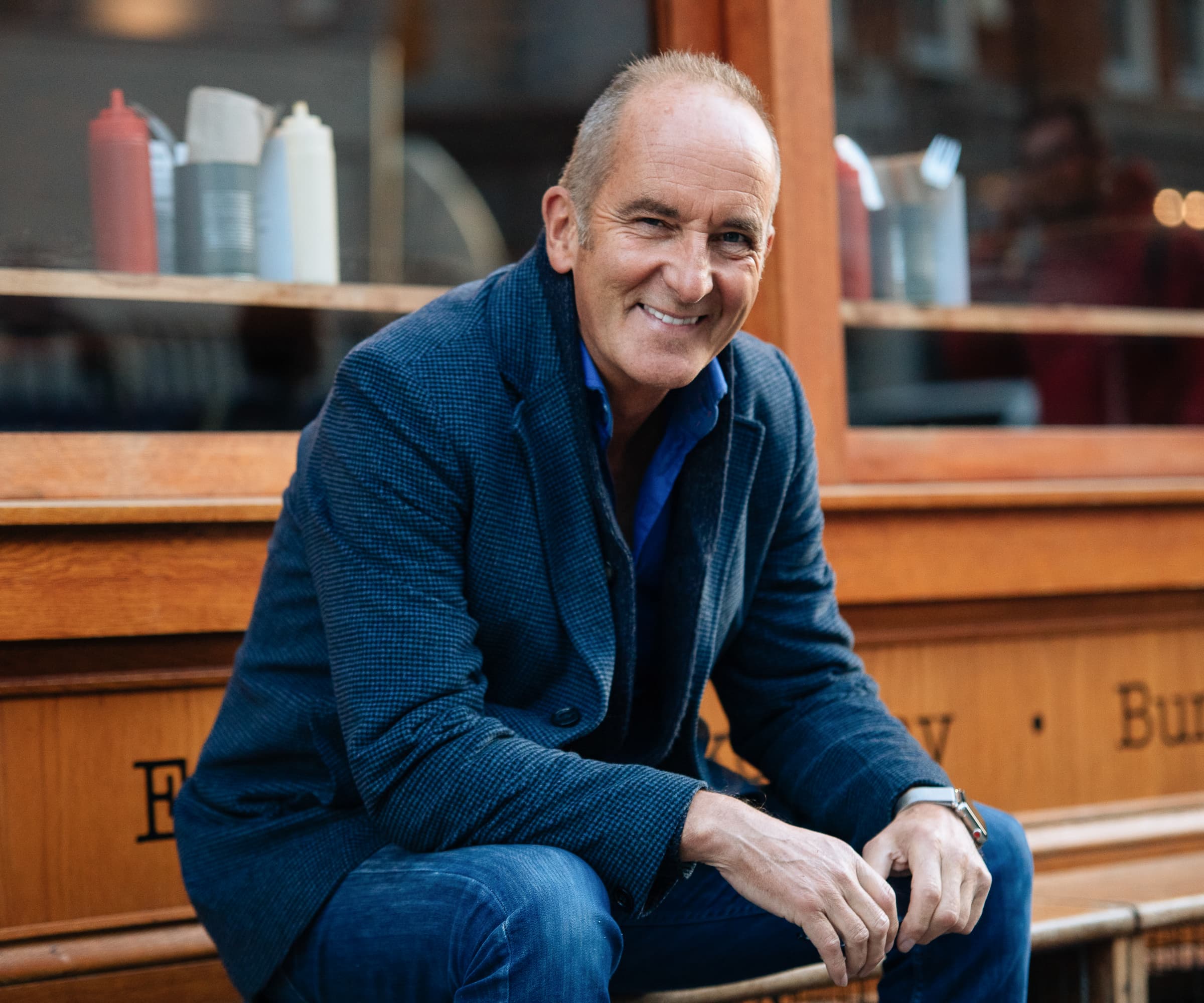 Kevin Mccloud smiling sitting on a bench