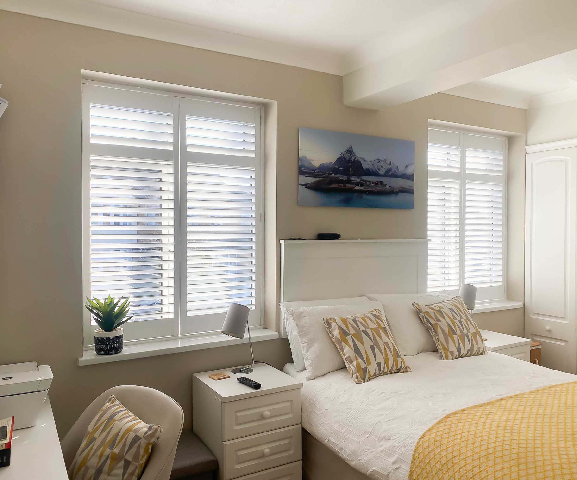 neutral bedroom with two windows with shutters
