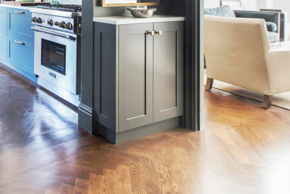 Brown hardwood floor with gray custom cabinet and view of kitchen space after renovation