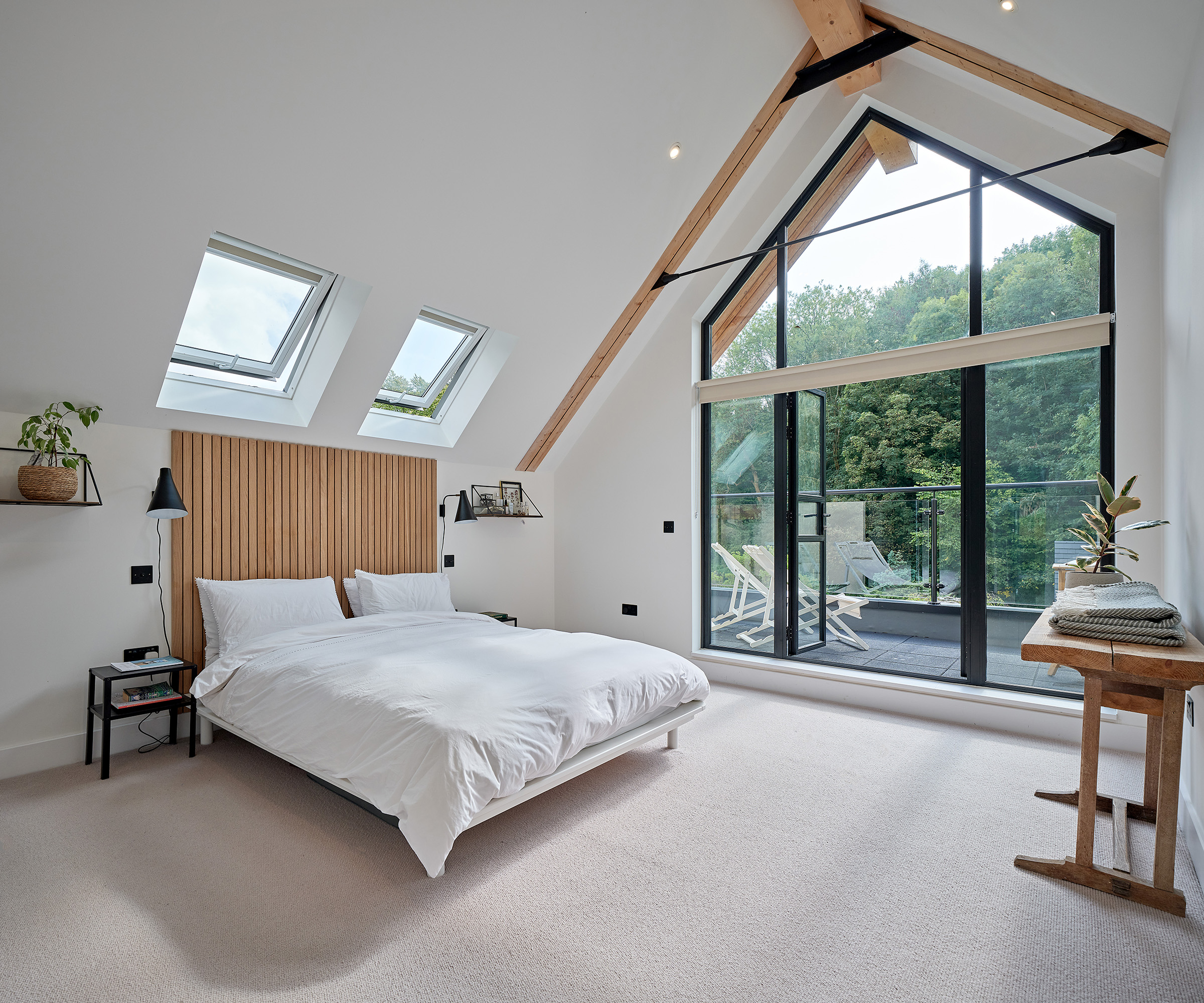 A view of a loft bedroom in a self build home with large glass doors opening onto a balcony