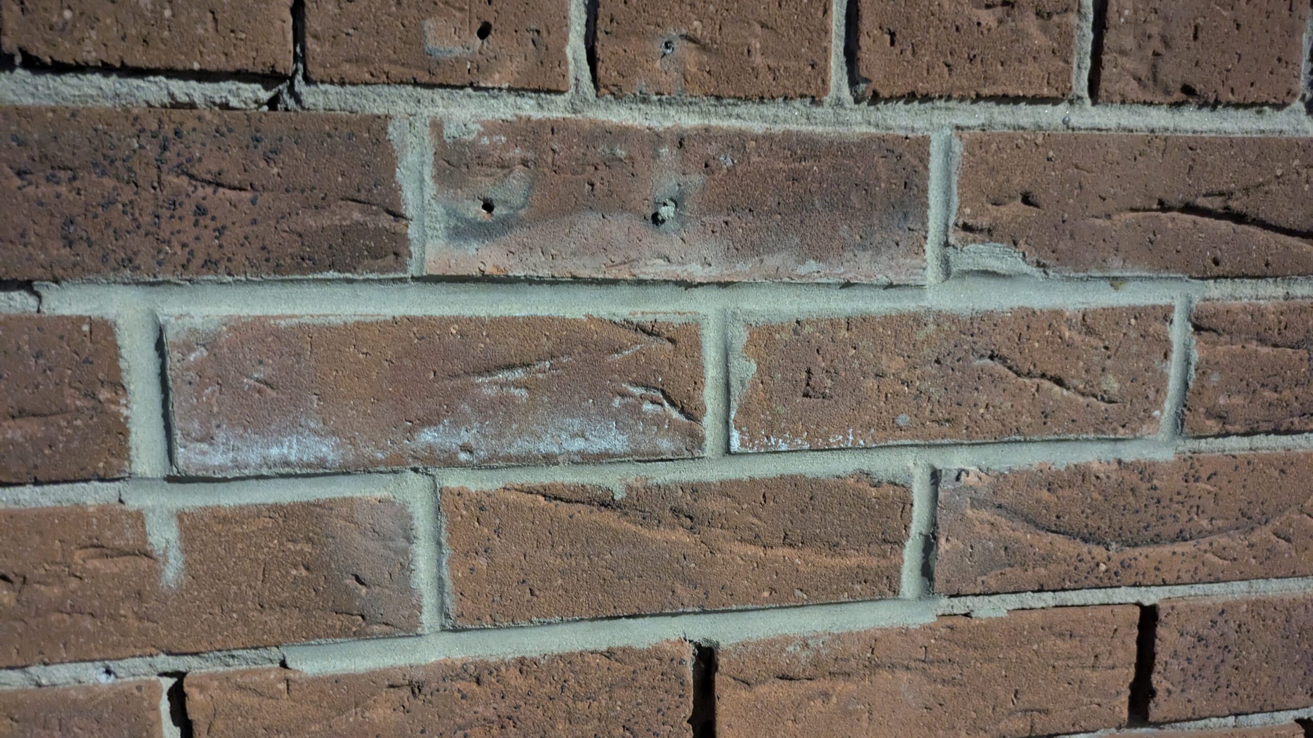 Some badly repointed brickwork with mess on the brick faces and gaps in the joints