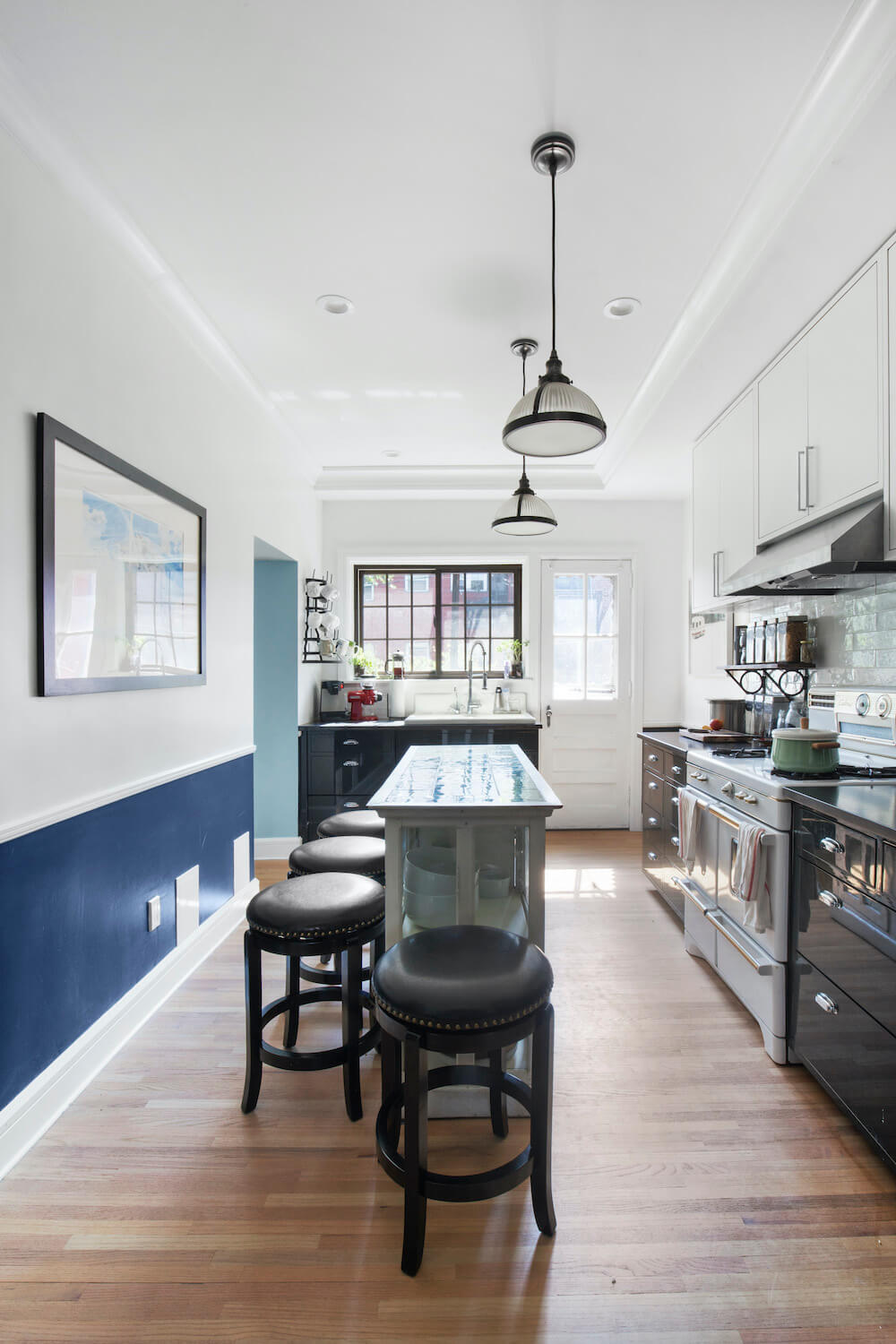 Kitchen island and black bar stools in a white and black kitchen after renovation