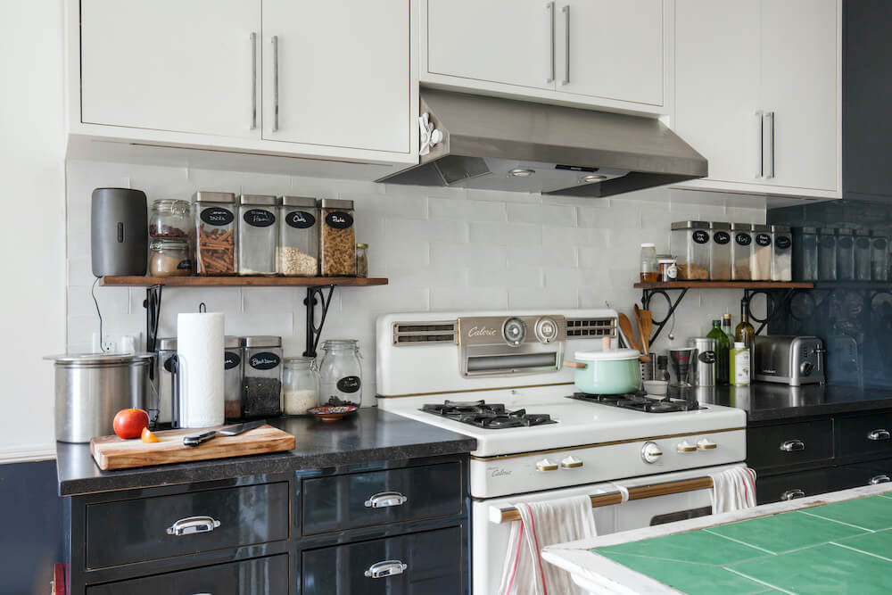 Matte white cabinets with glossy charcoal lower cabinets with a white cooking range after renovation