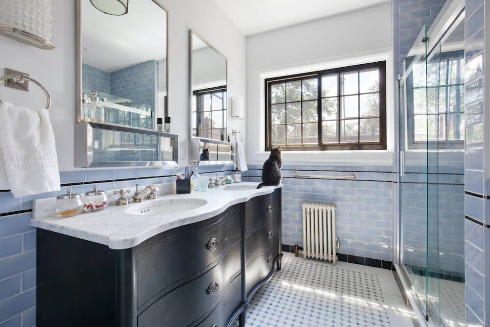 Blue half tiles in a white bathroom with glass shower separator and blue penny round tiles after renovation