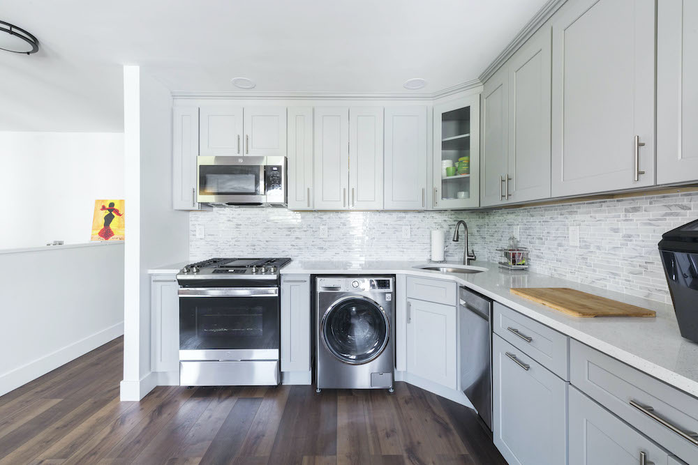 Light gray open kitchen with white quartz countertop and closed cabinets after renovation