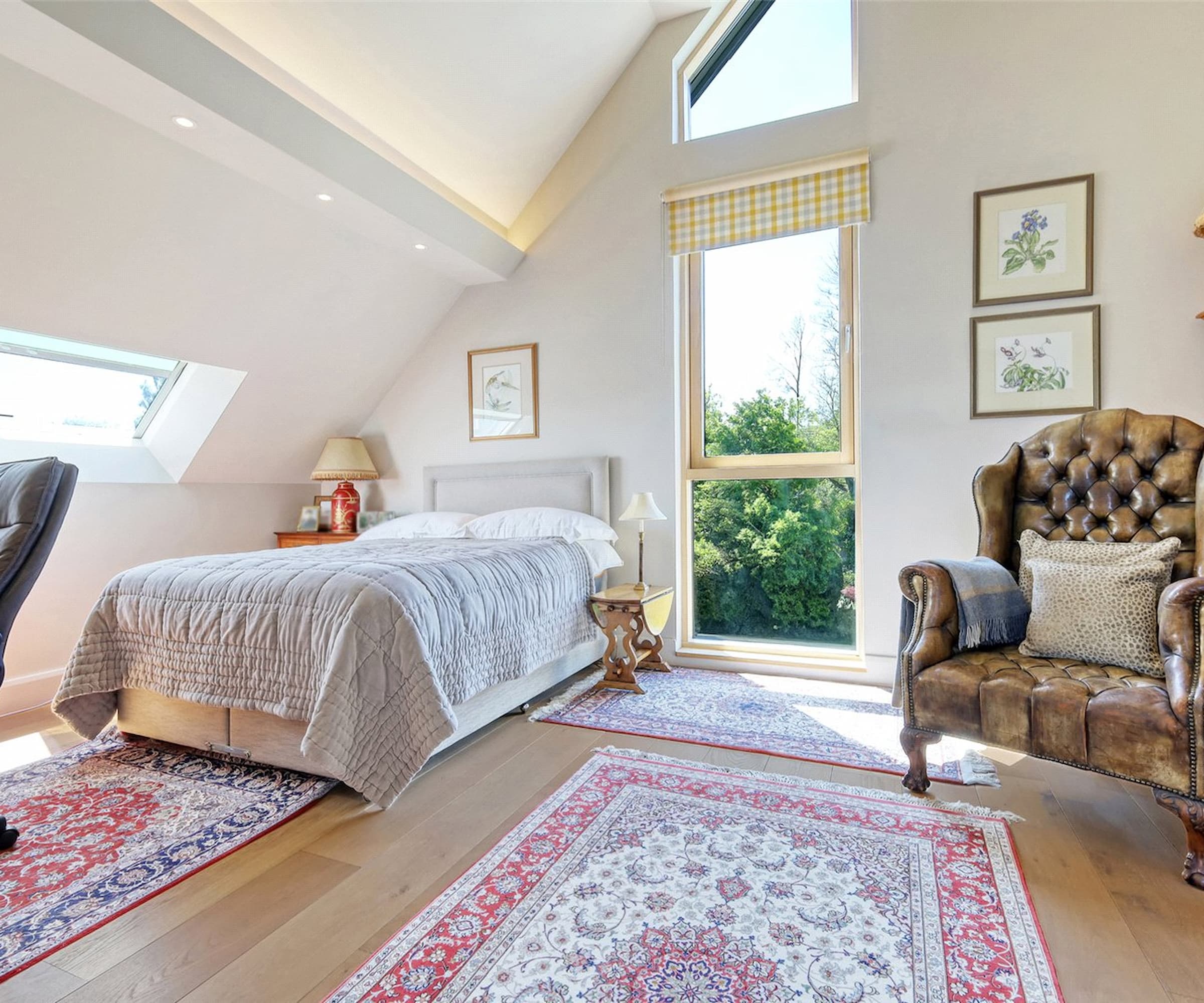 A bedroom with a slanted ceiling and a large window and roof light