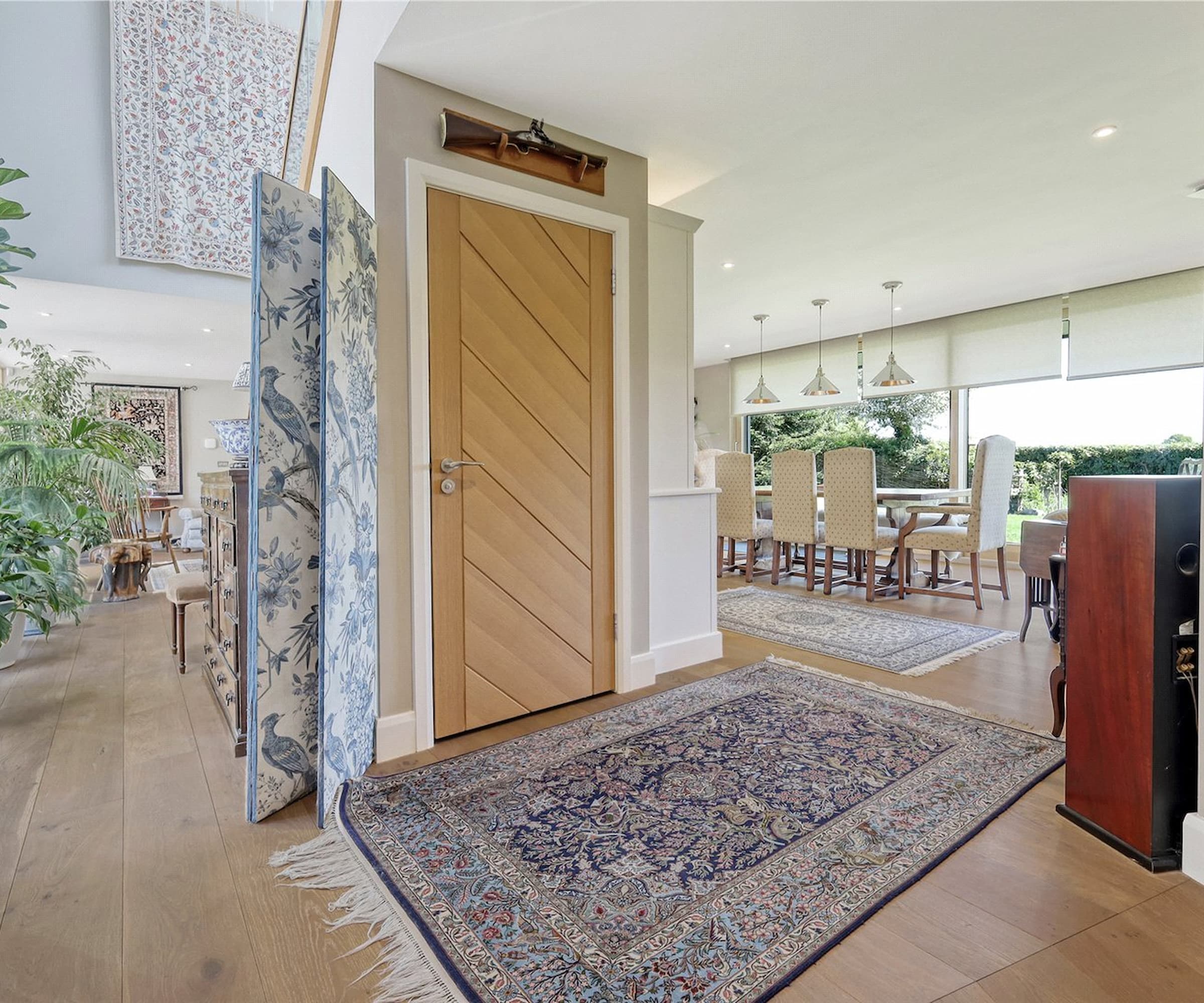 A hallway with an elevator with an open plan design leading to a dining area