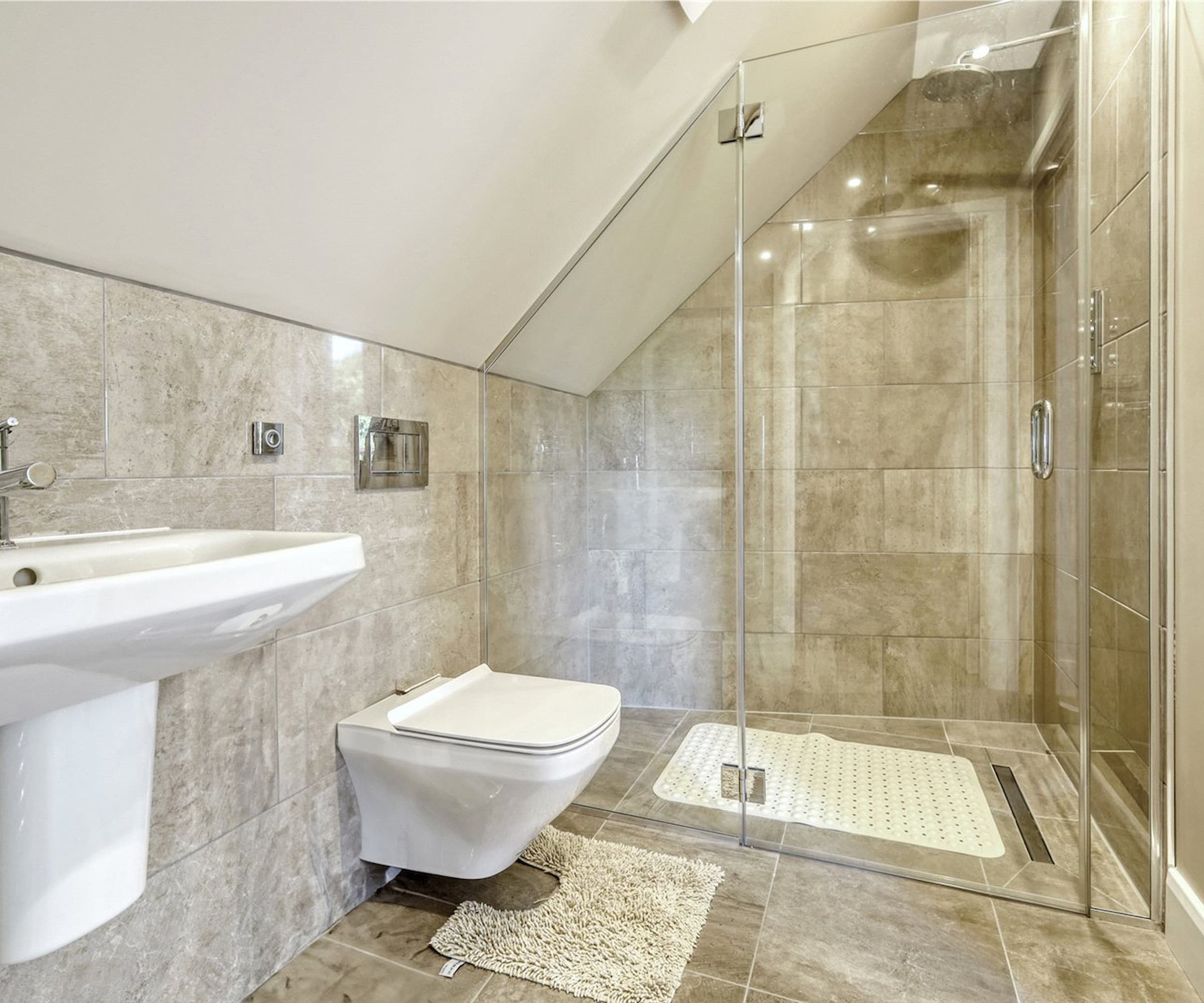 A slanted ceiling bathroom with white ceramic tiles and a walk in shower