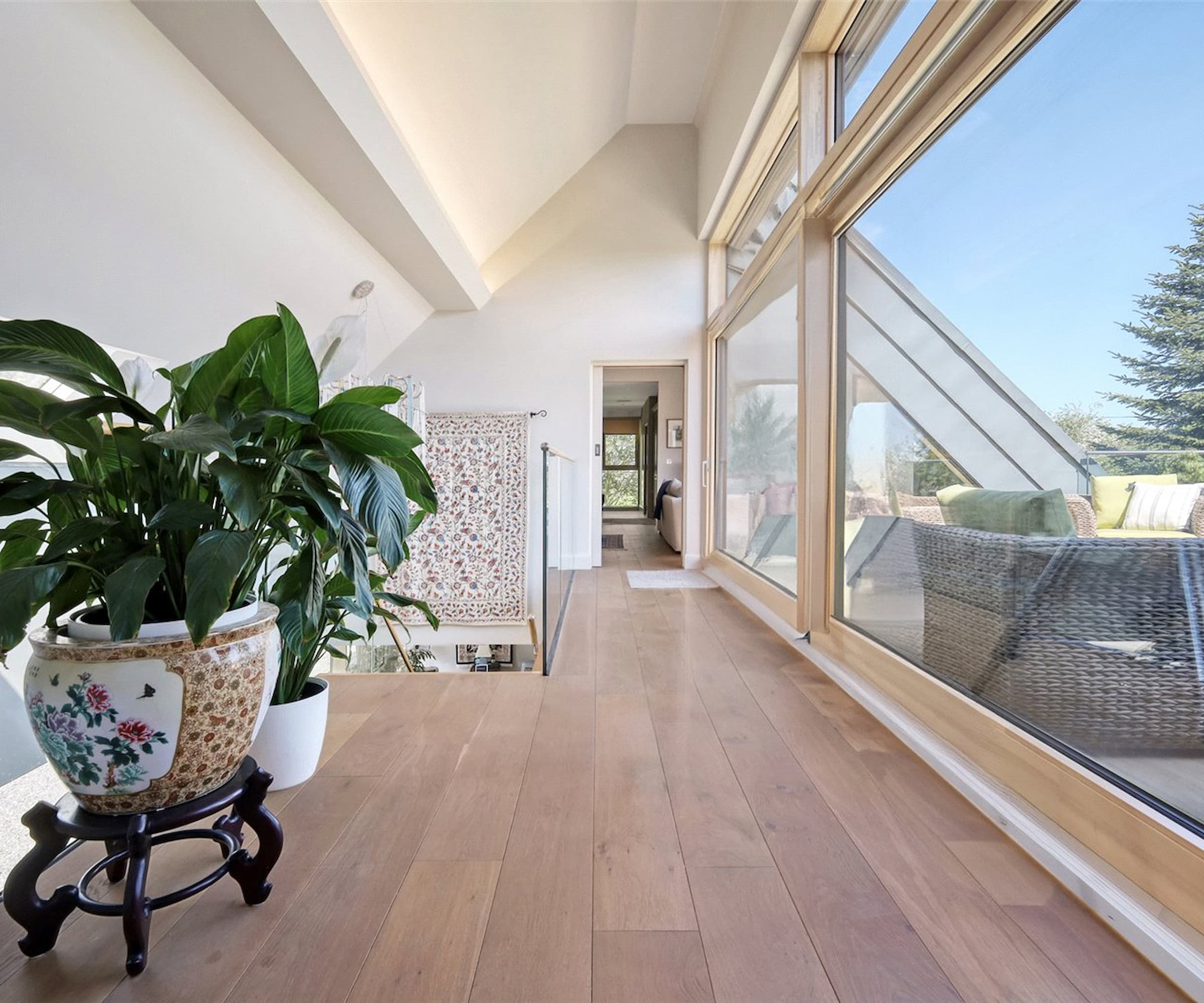 An upstairs hallway with a tall window next to a balcony