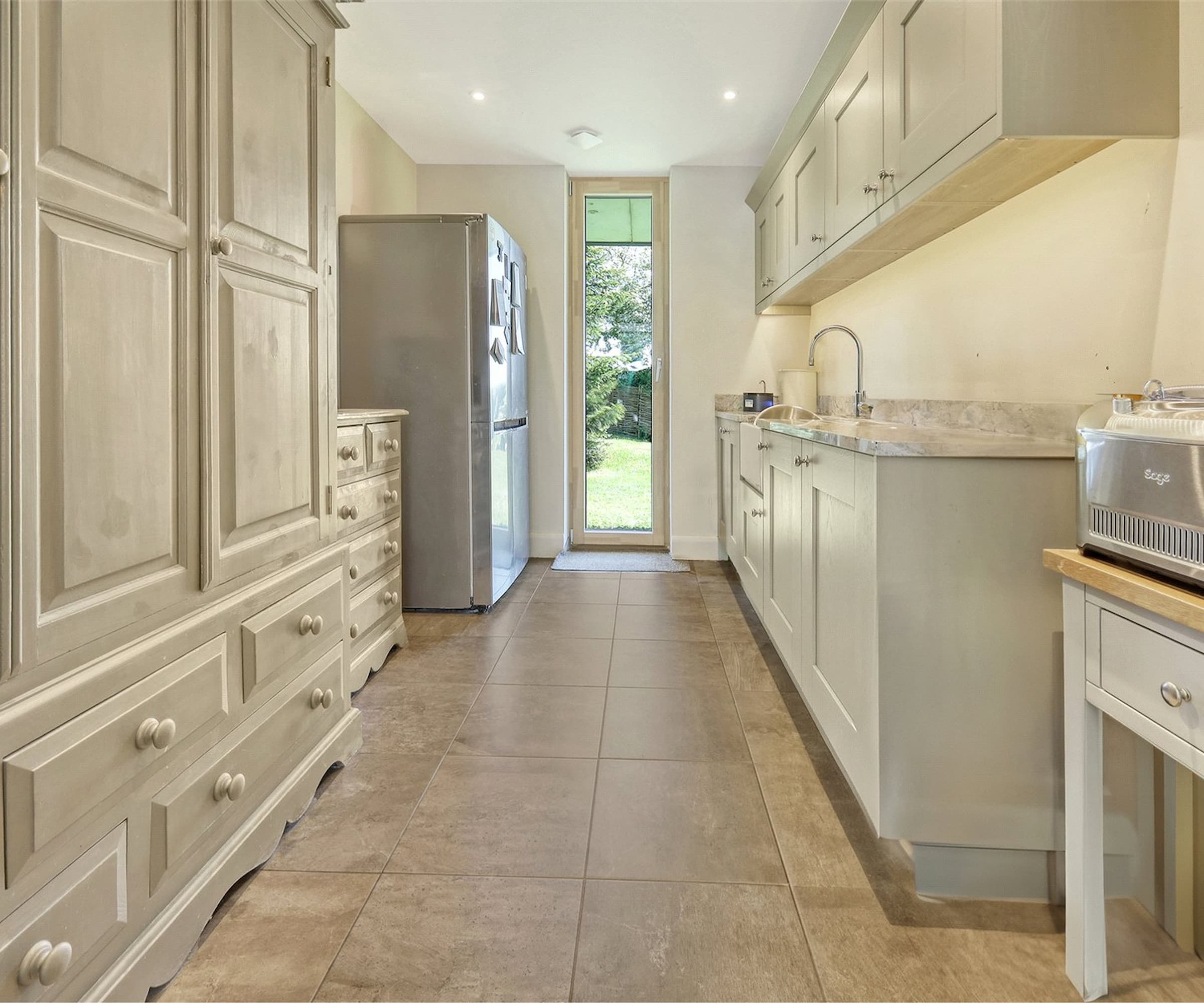 A narrow white kitchen/utility room with ceramic flooring