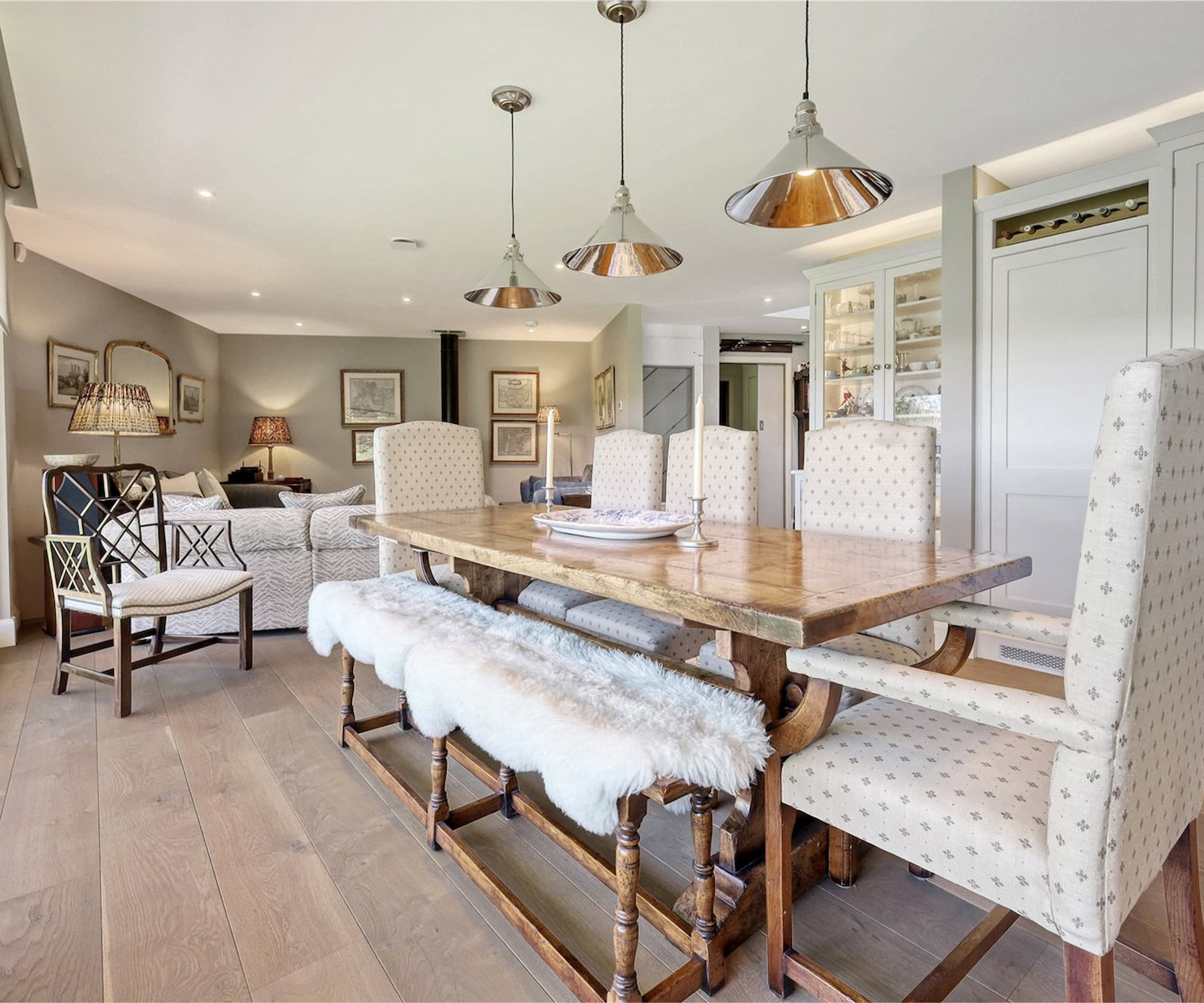 A dining area with a wooden dining table and see through kitchen cupboards