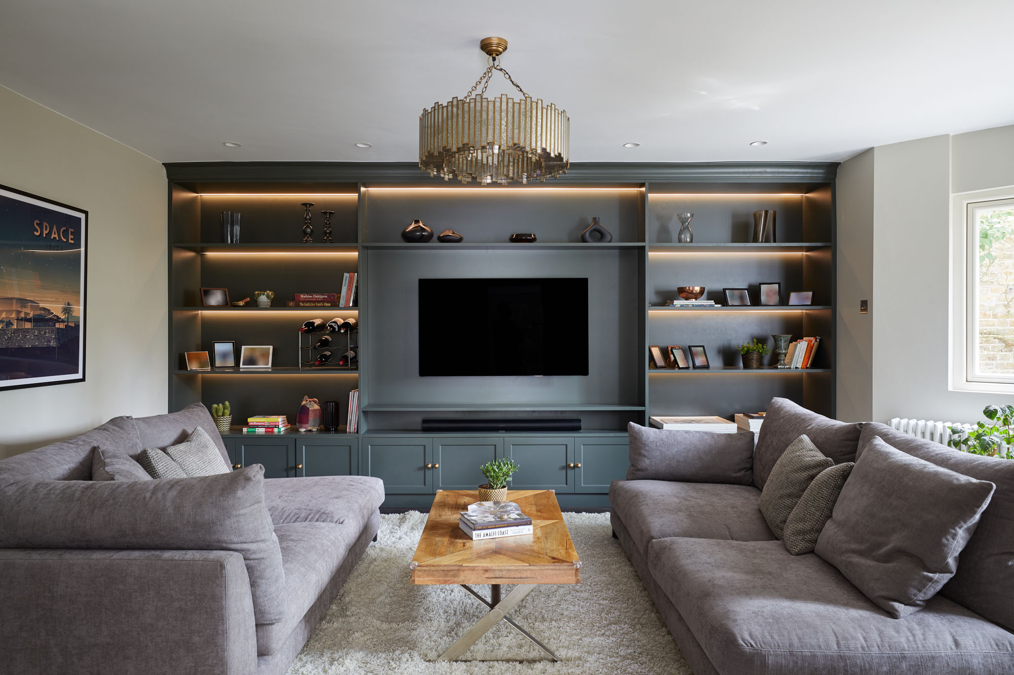 A living room with dark grey media wall with two grey sofas either side and a small wooden coffee table in the middle
