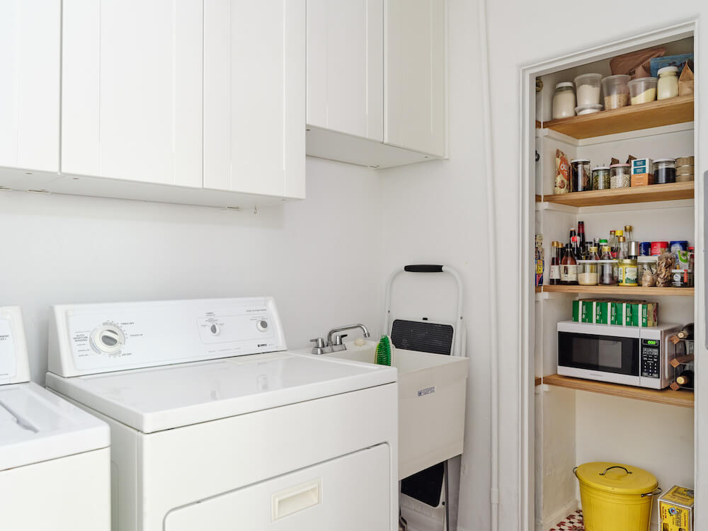 laundry area with utility sink and white cabinets and storage area after renovation