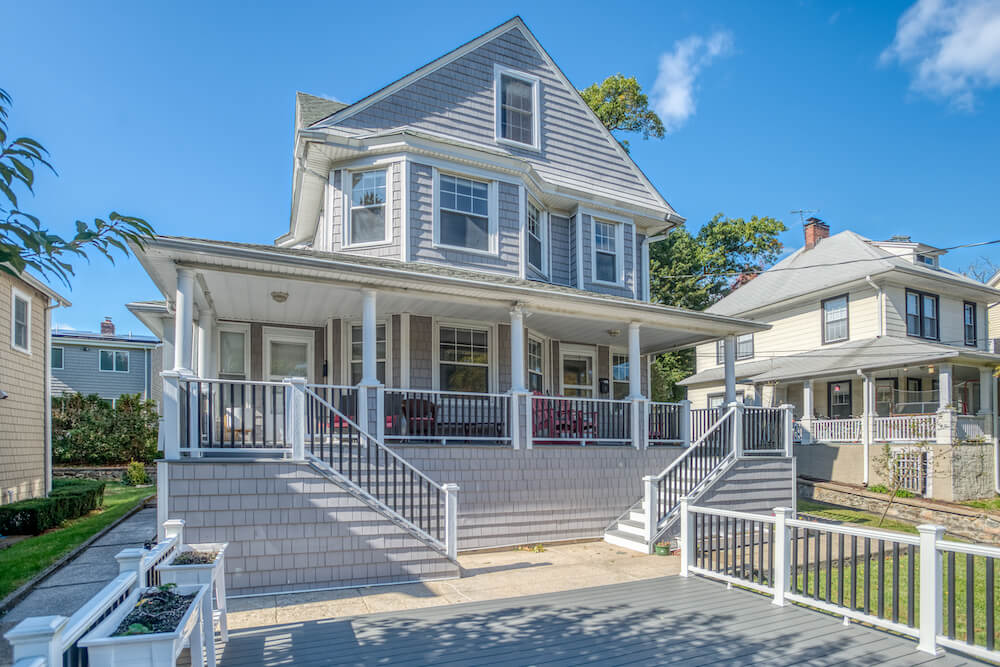 exterior of house with vinyl siding and staircase and porch with railings after renovation 