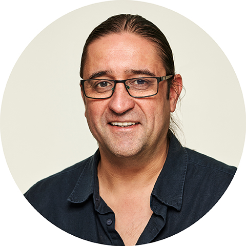 male with dark hair pulled back off face wearing glasses and navy shirt
