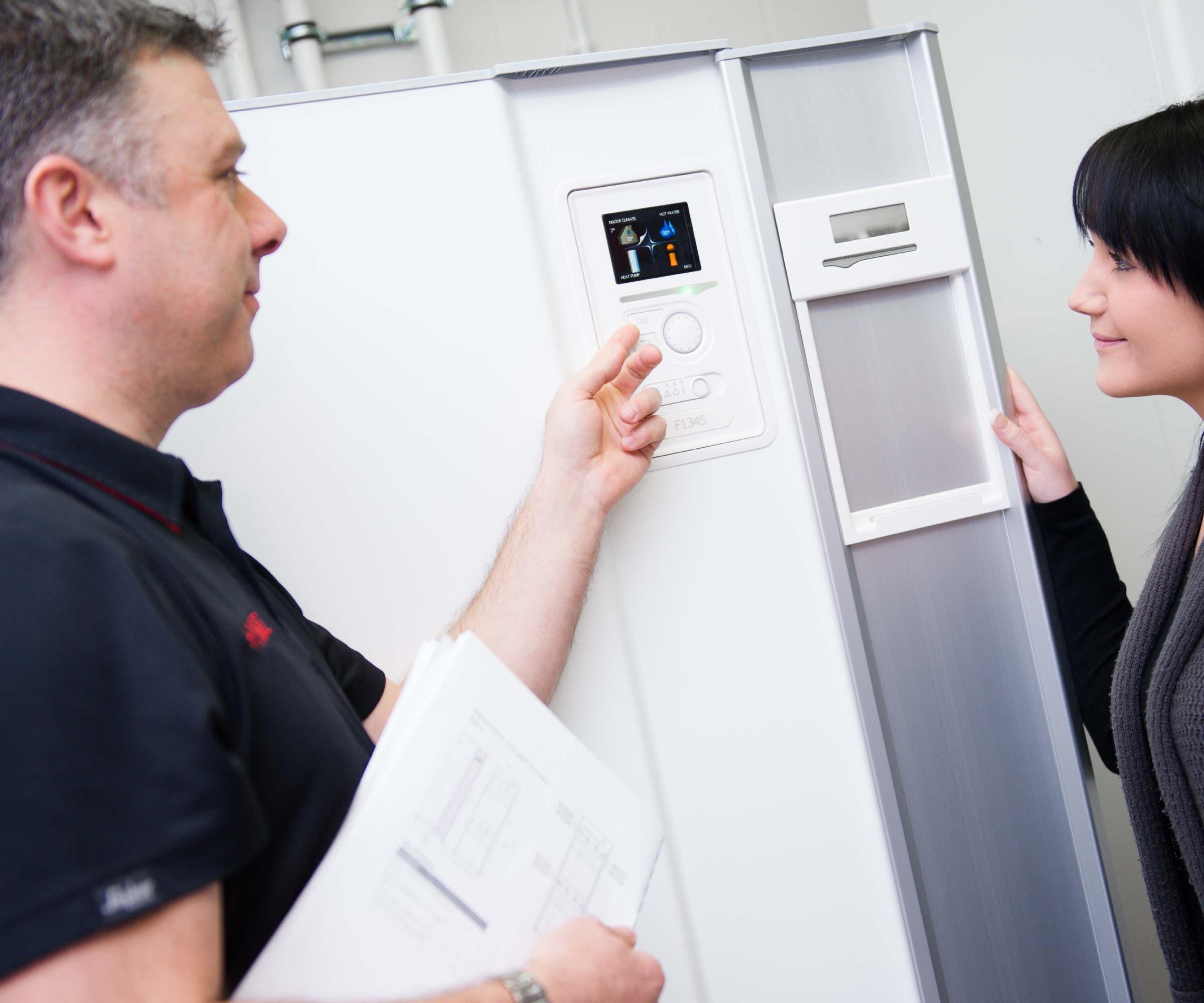 heat pump installer pointing to control display on unit and talking to homeownere