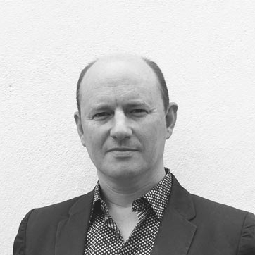 black and white headshot of male wearing dark suite with spotted shirt