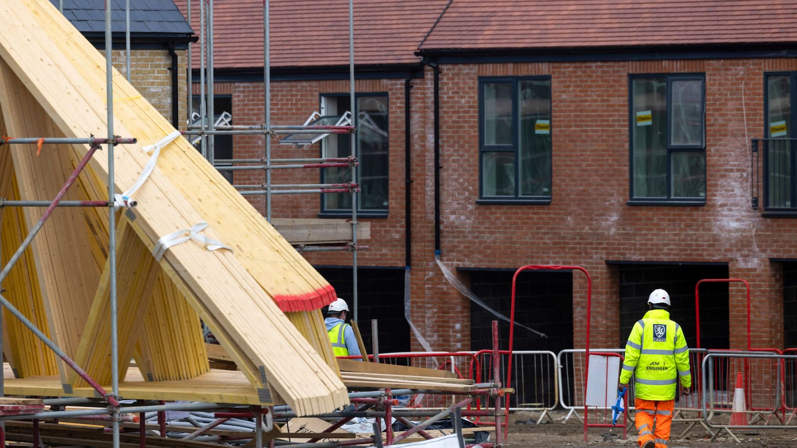 A builder and timber next to a brick house shell
