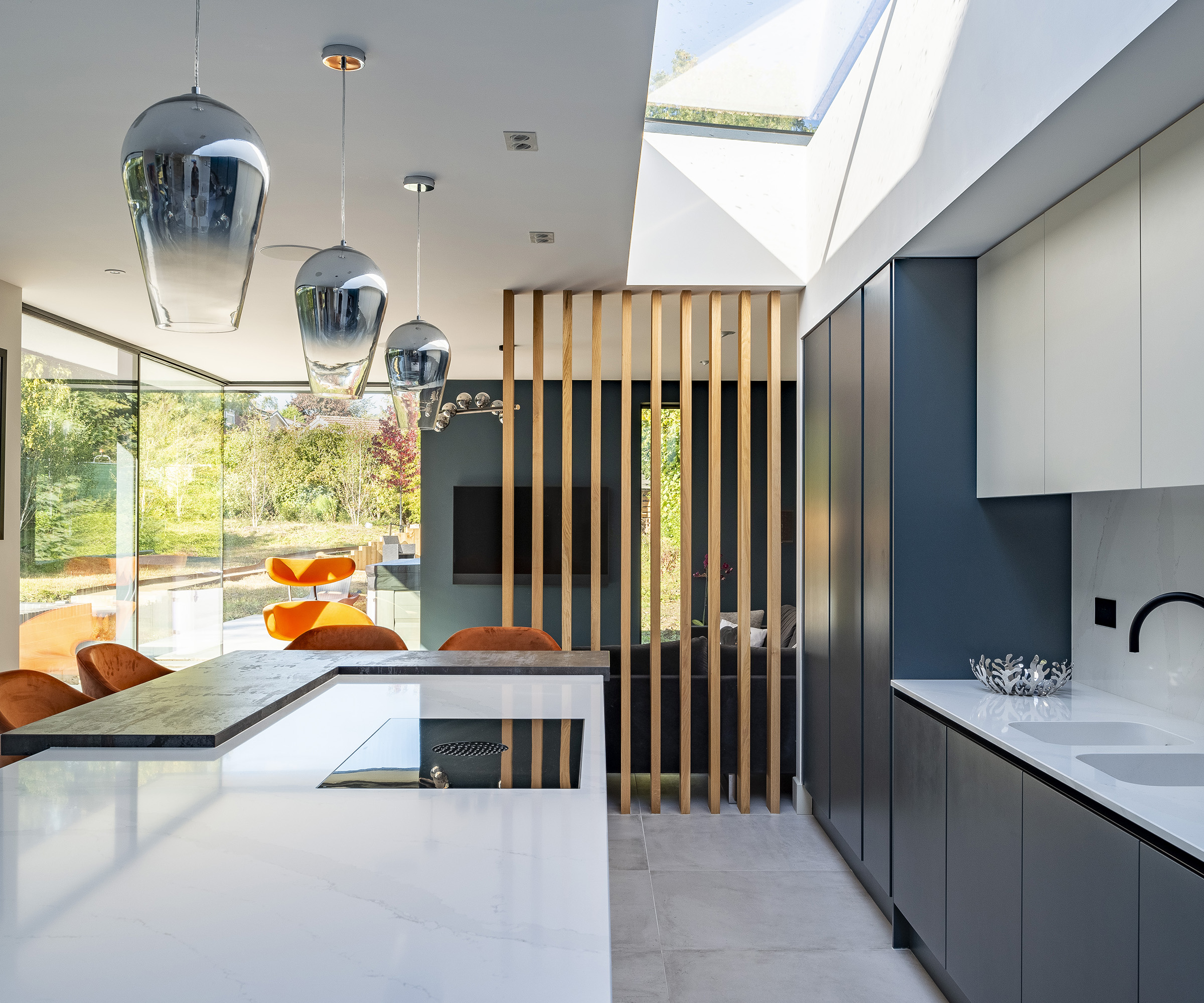 A kitchen in a broken plan kitchen and living room area cordoned off with a wooden rail