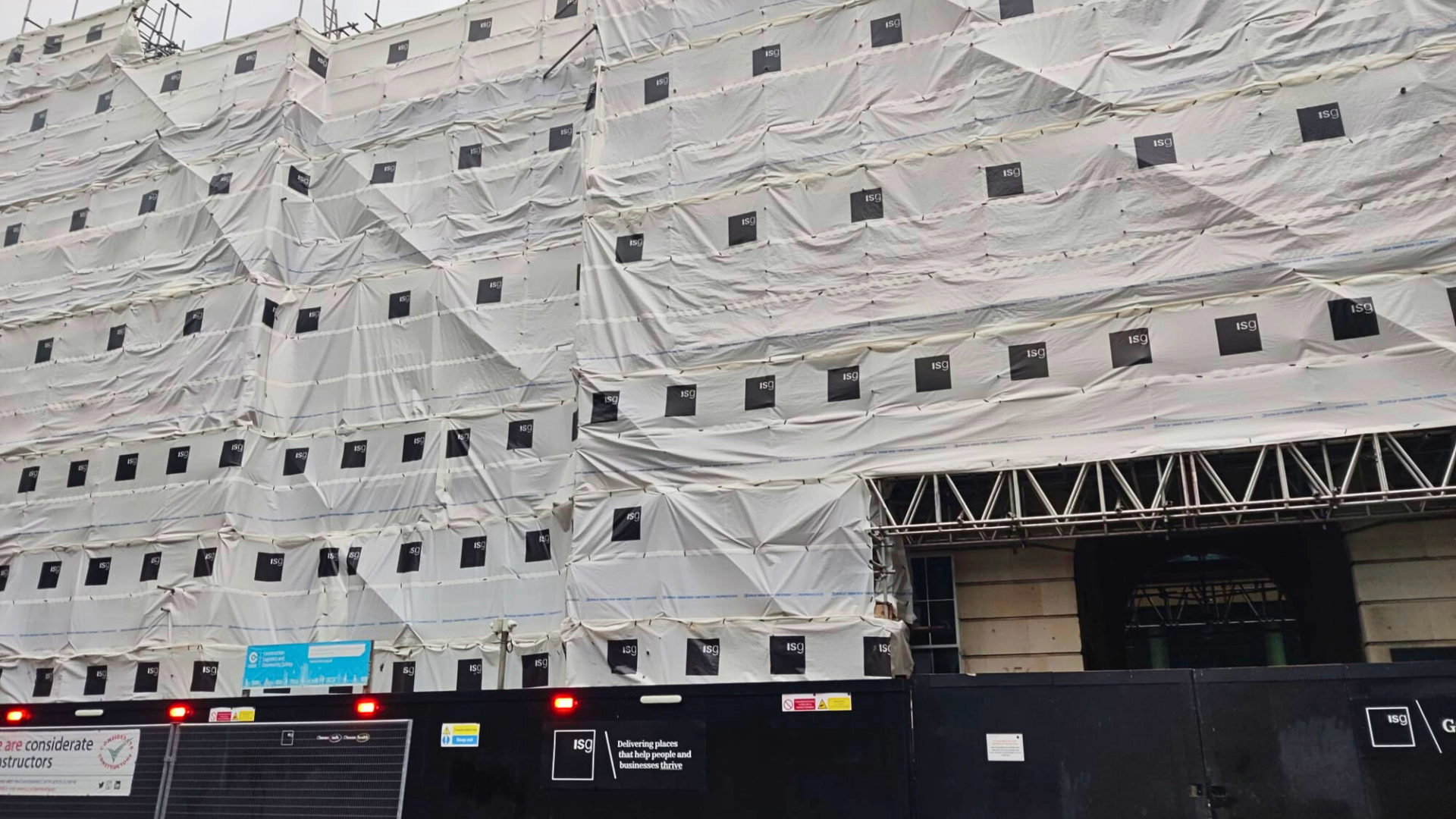 Outside of a closed ISG project with white scaffold sheeting and black hoarding with ISG signagne. Lawyers share five considerations for subcontractors worried about the impact that ISG