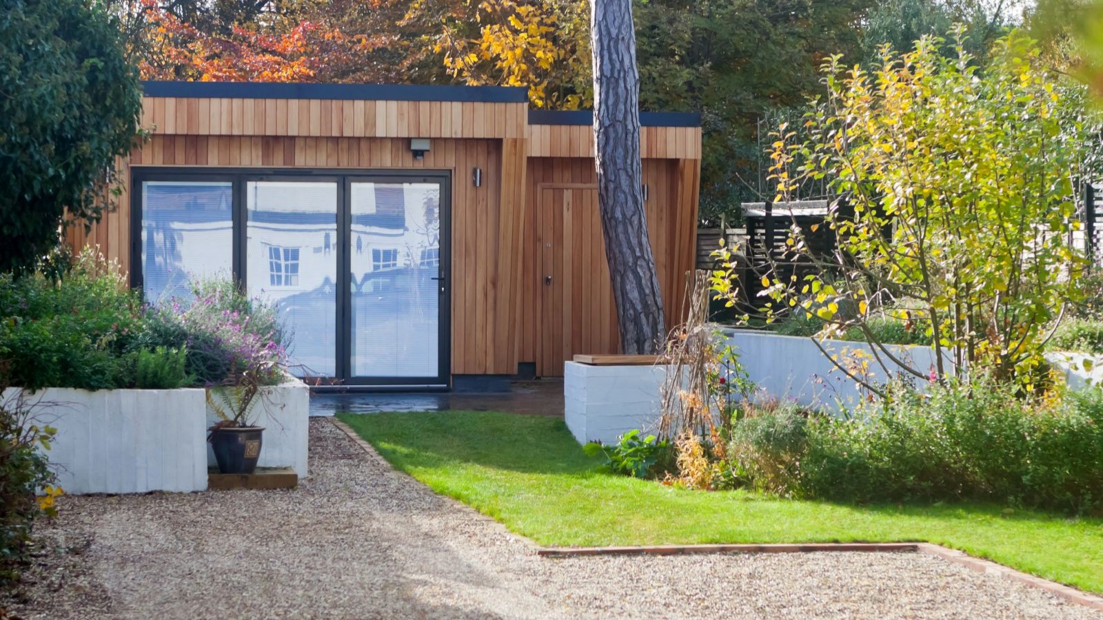 A garden room with timber cladding on the exterior and a lawn to the front