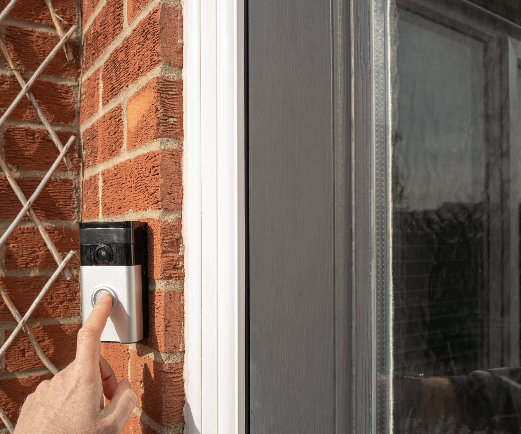 A hand pressing the button on a Ring video doorbell