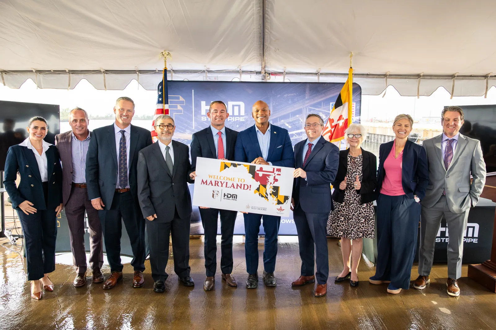 A group of people in suits hold a sign that says "Maryland" at a ceremonial event
