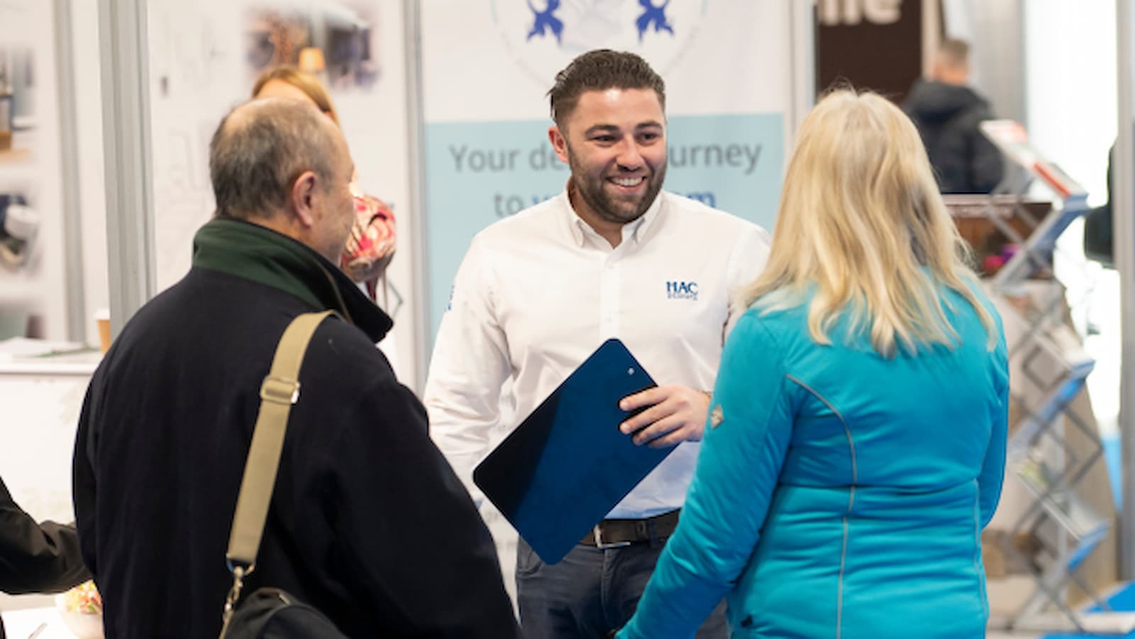 An exhibitor talking to a couple at the Homebuilding &amp; Renovating Show