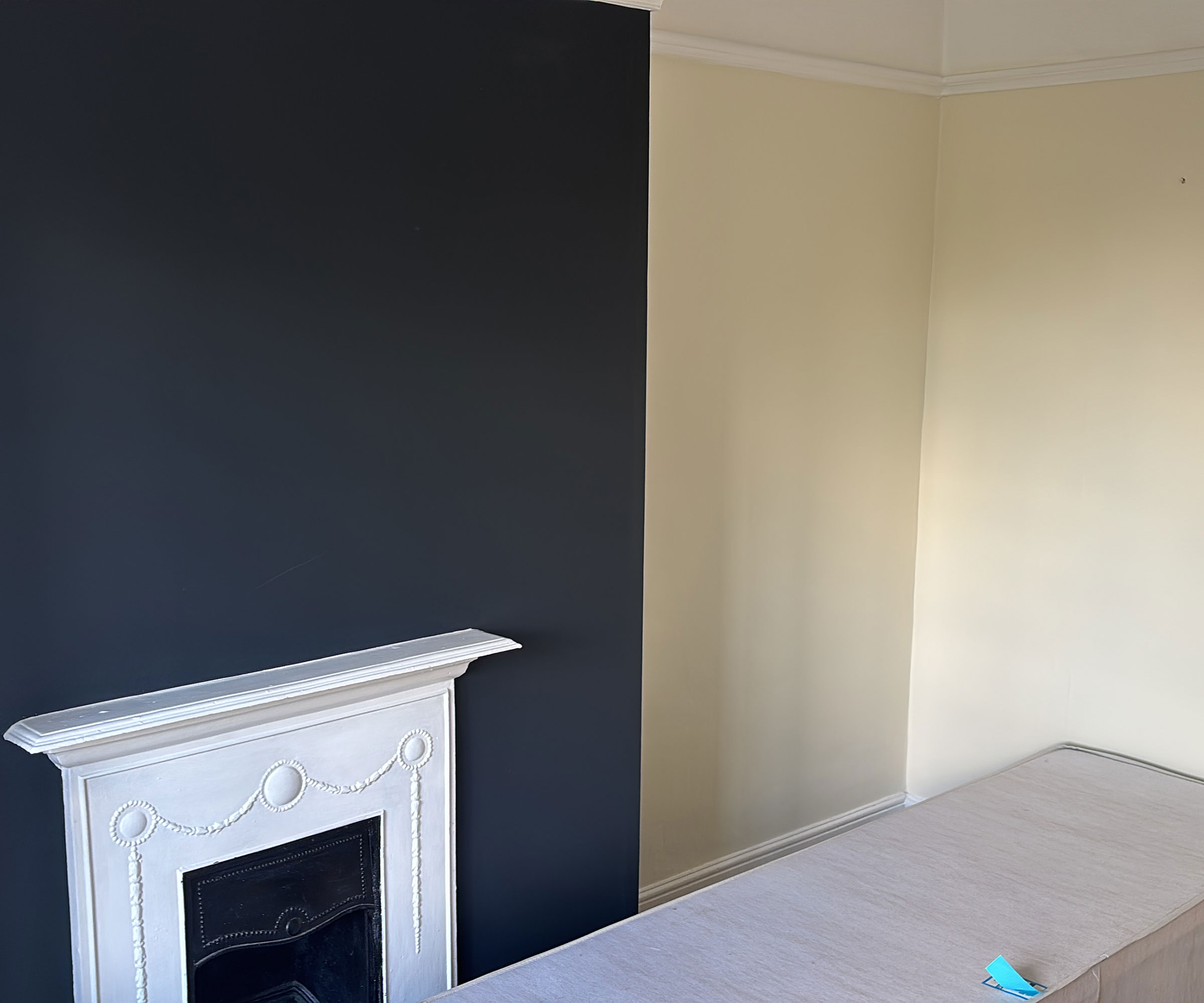 partially decorated bedroom with black painted chimney breast and white fireplace with neutral walls