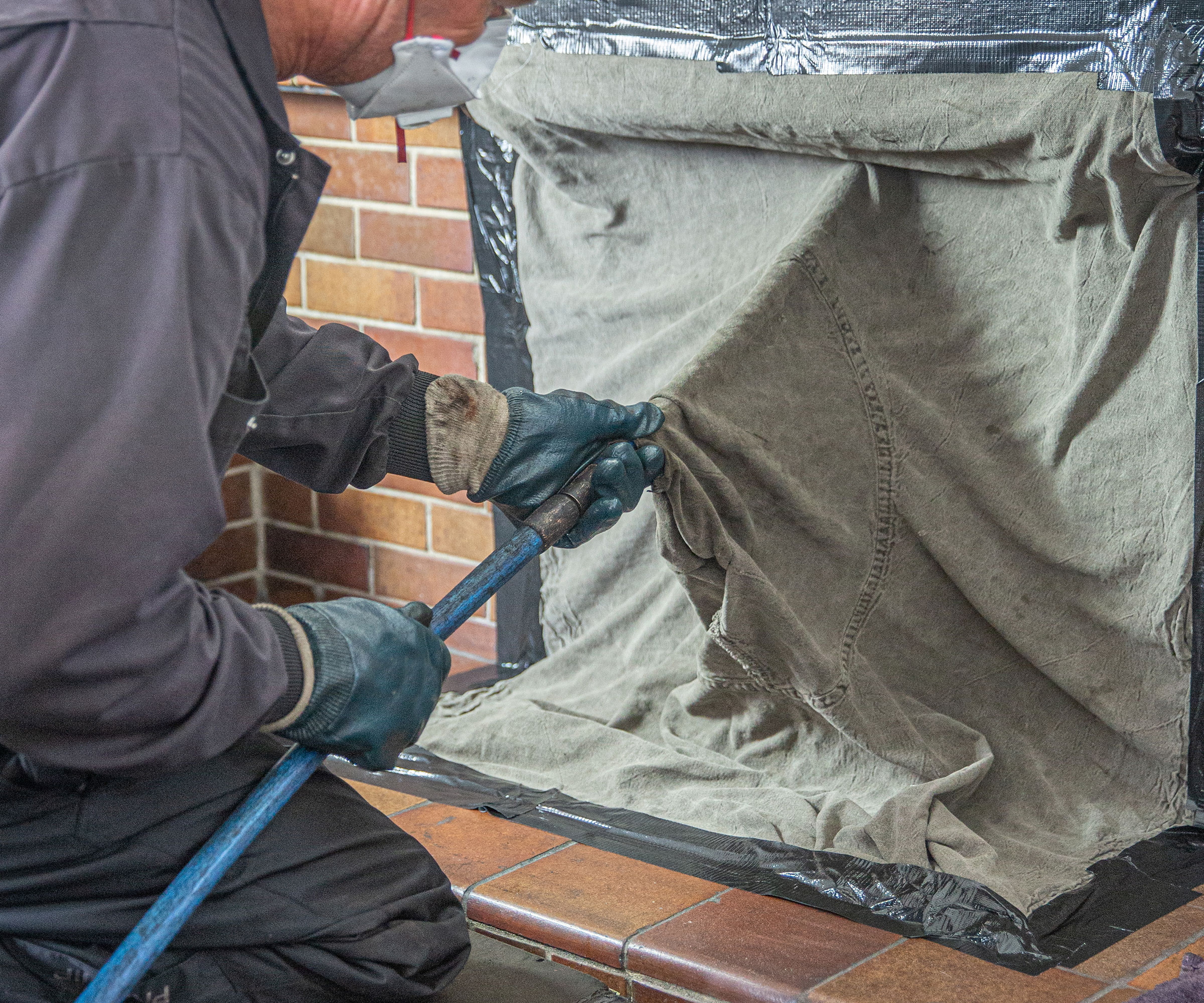 man in overalls sweeping a chimney