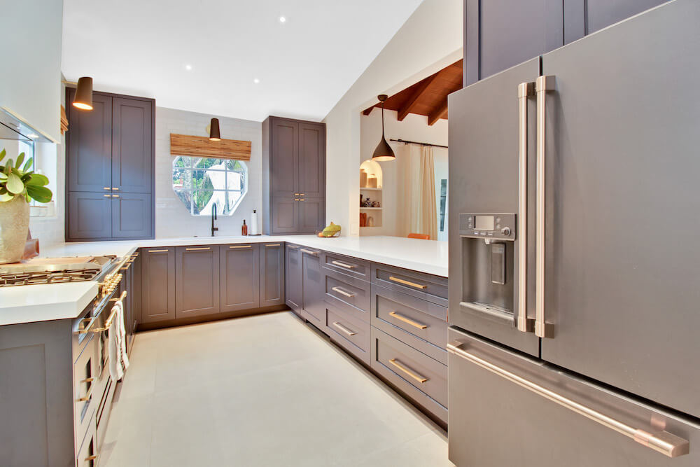 U-shaped kitchen with dark blue shaker cabinets, white quartz countertops, French-door fridge, and a wide pass-through to the living room.