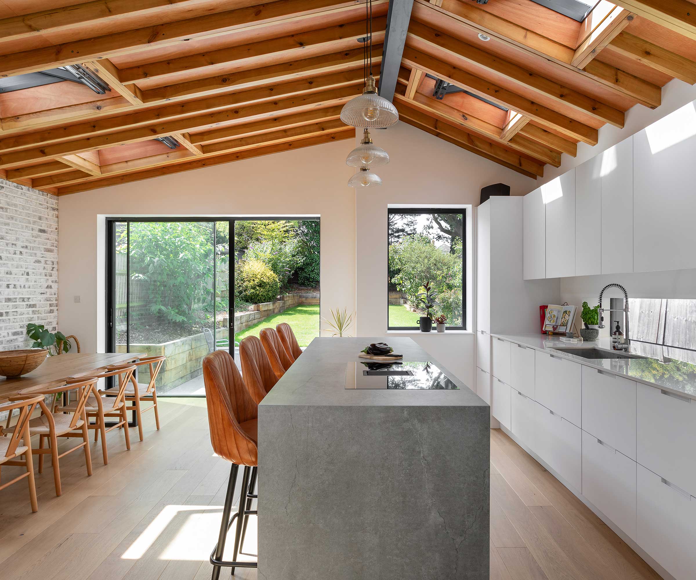 kitchen extension with a vaulted ceiling, exposed timber trusses, a white kitchen and large kitchen island