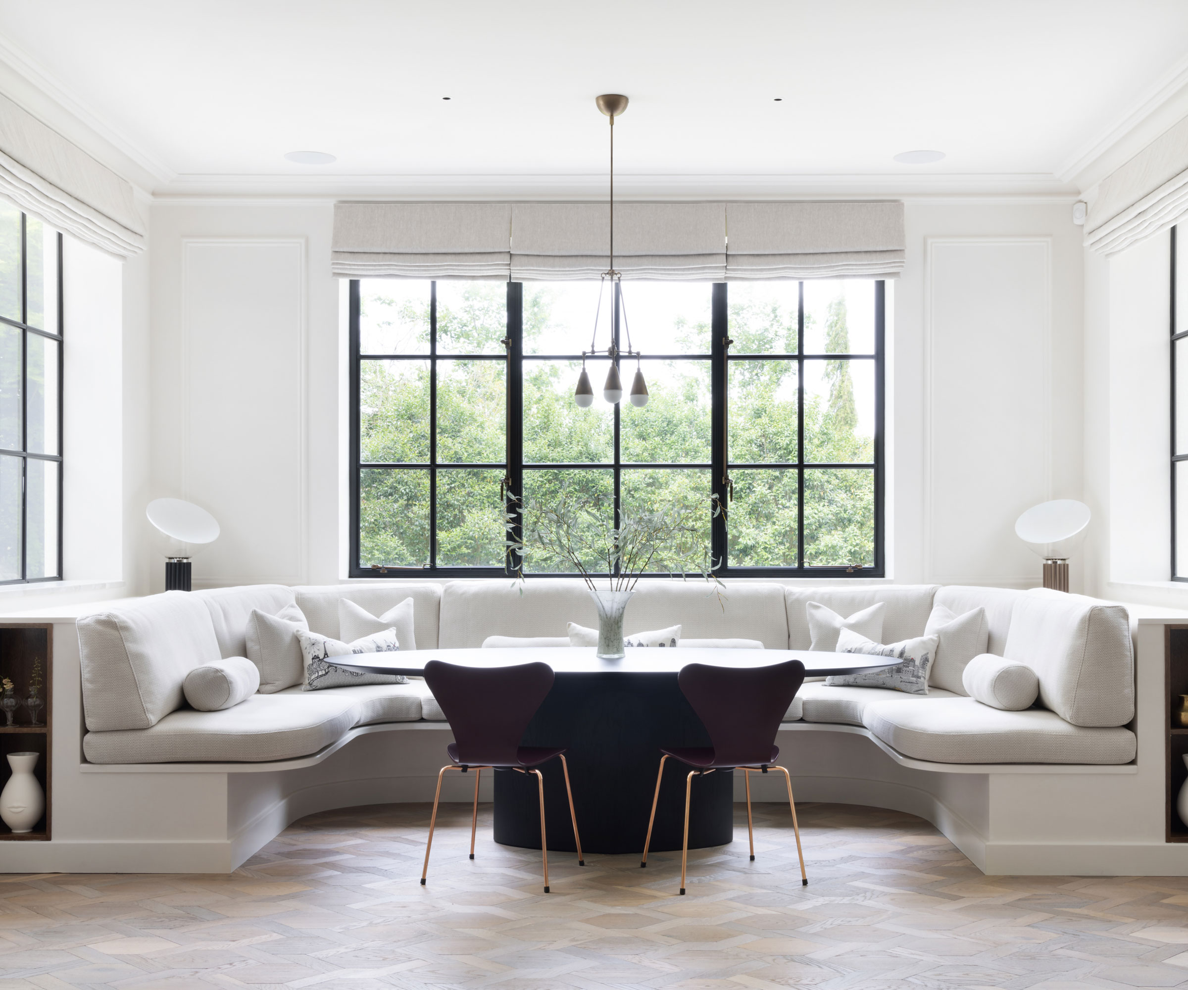 modern dining space with banquette seating and black metal framed window