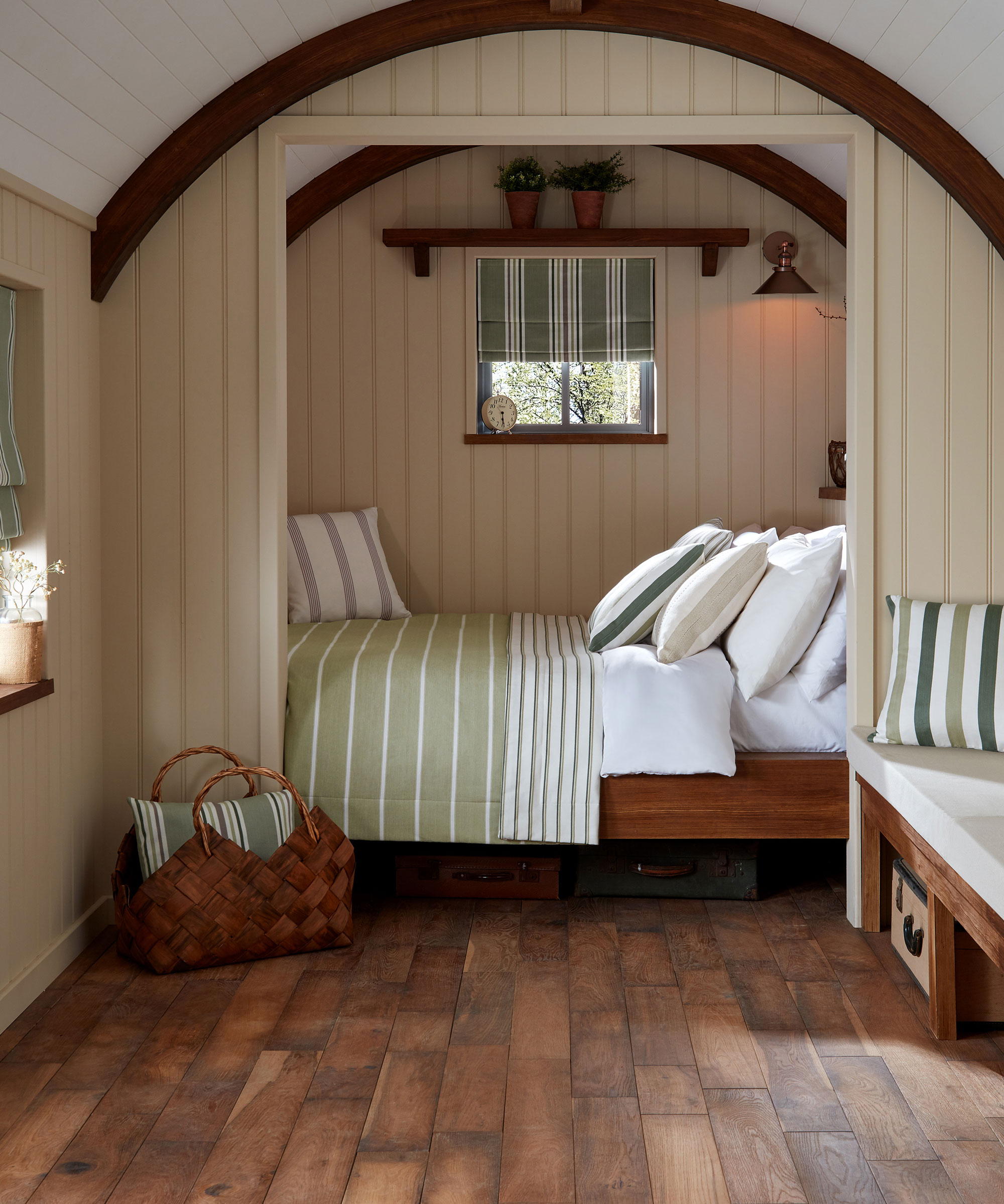 Bedroom in shepherds hut with cream vertical wall panelling