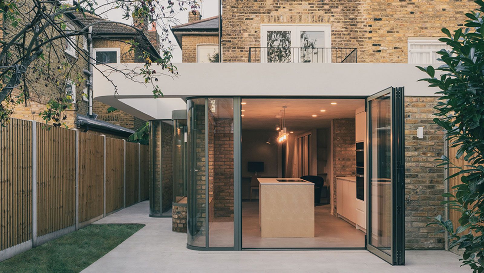 single storey flat roof extension with curved glass wall and bi fold doors