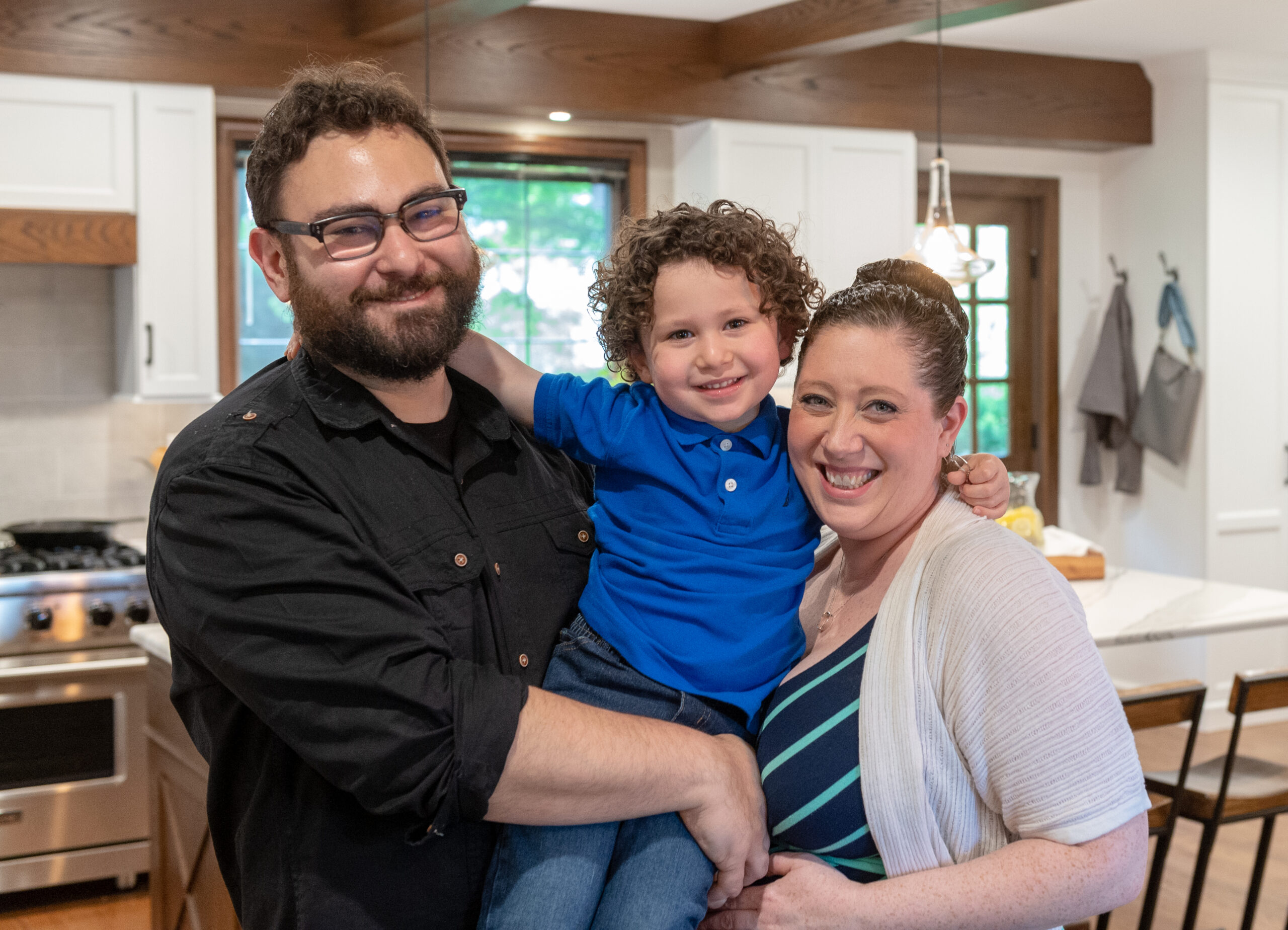 Man with glasses, woman, and child in their Tudor-style kitchen