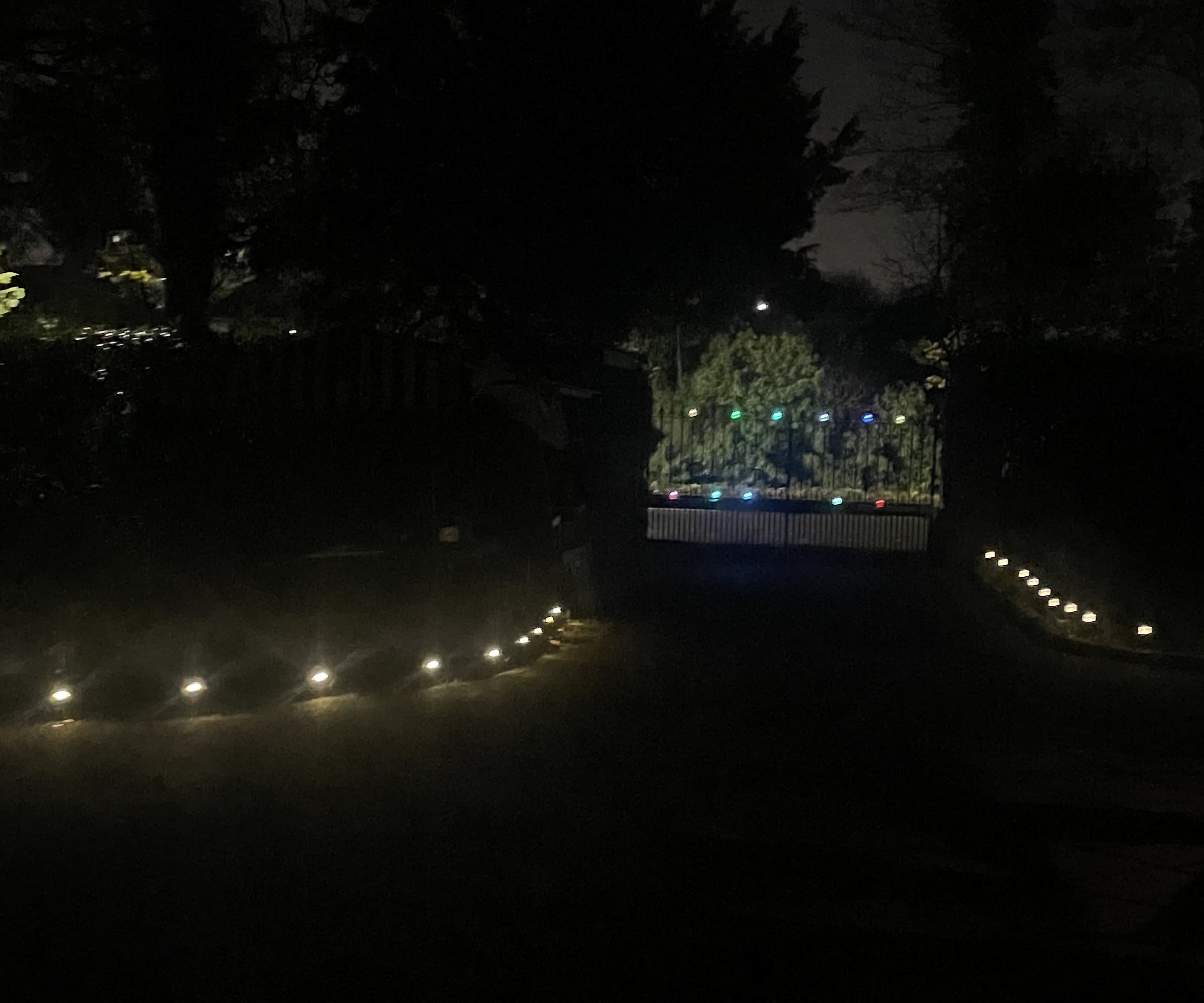 A dark driveway lit up on both sides by solar lights