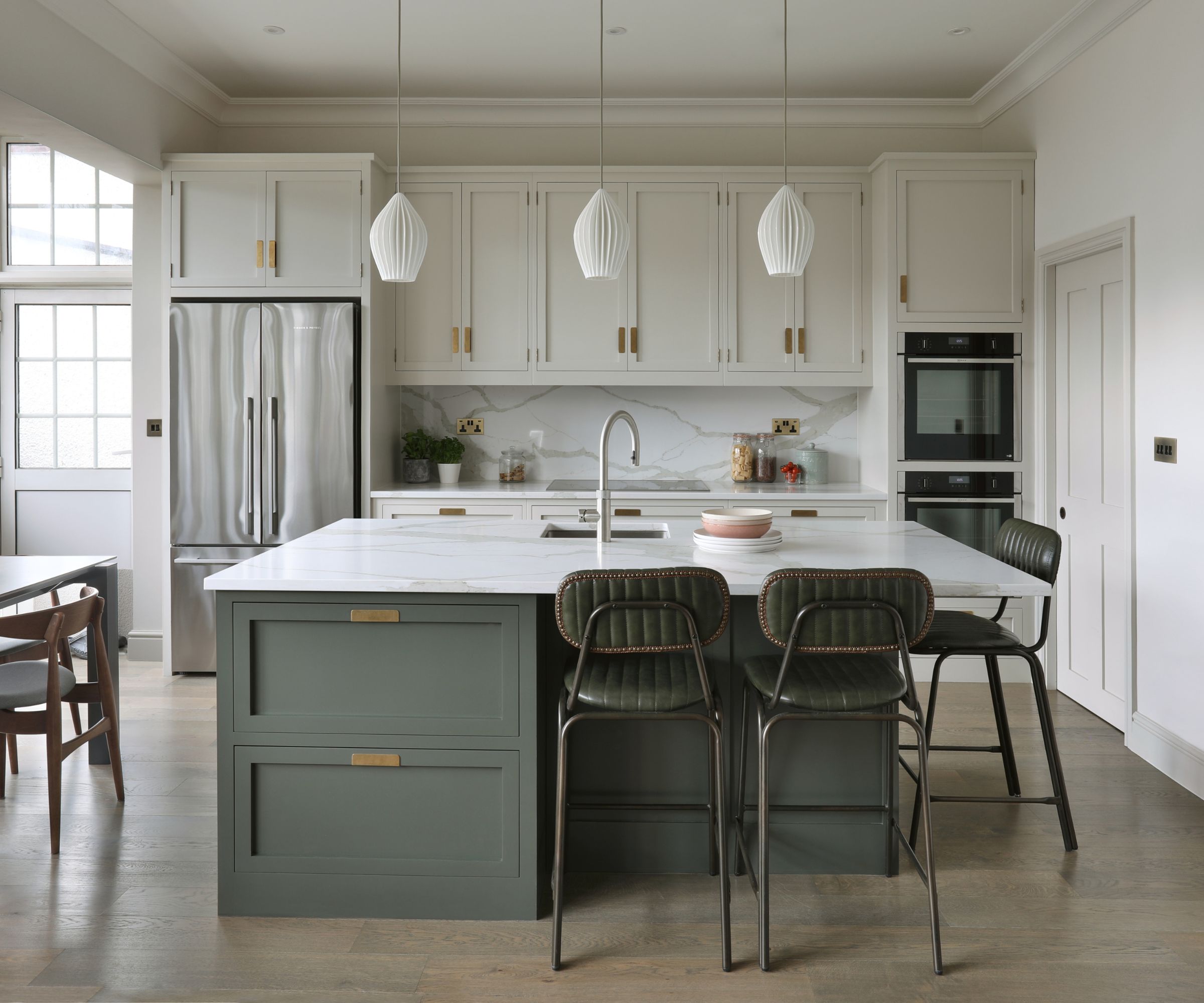 Bright white kitchen with green island and marble worktop