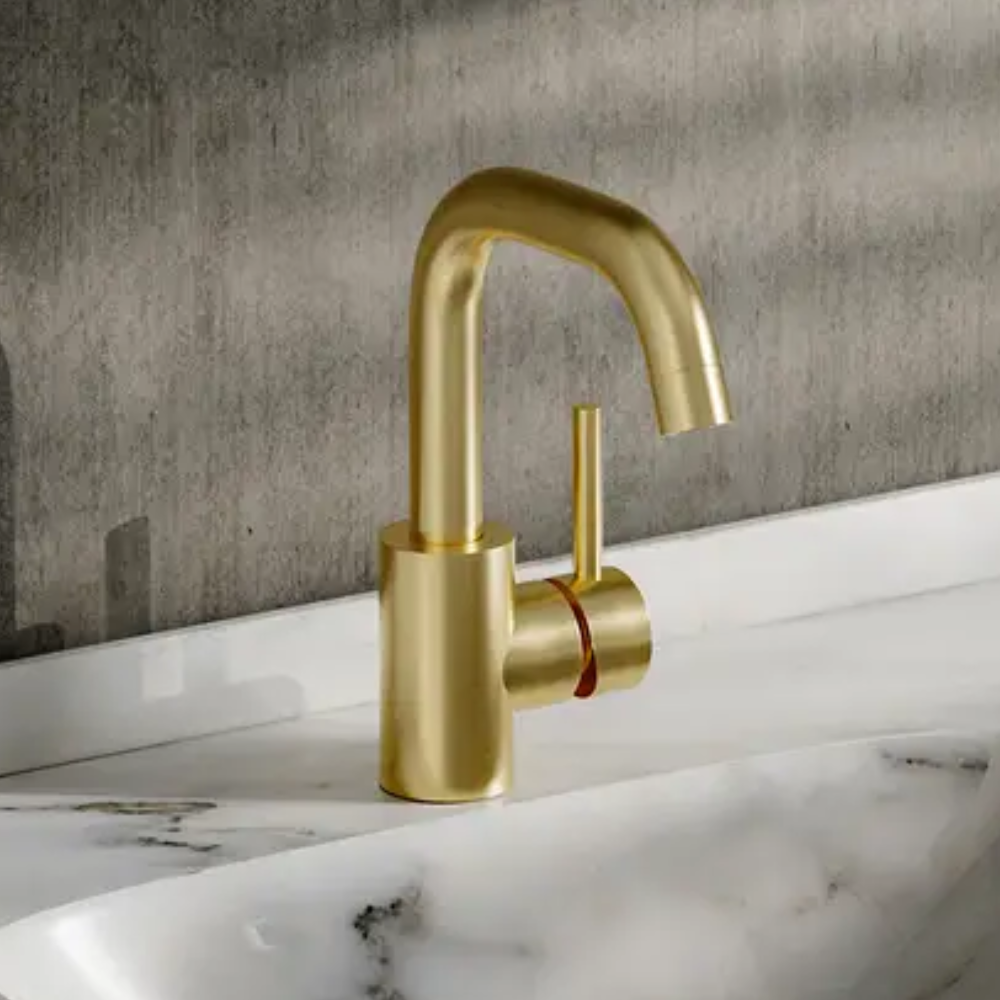 Gold tap on marble sink behind a grey wall
