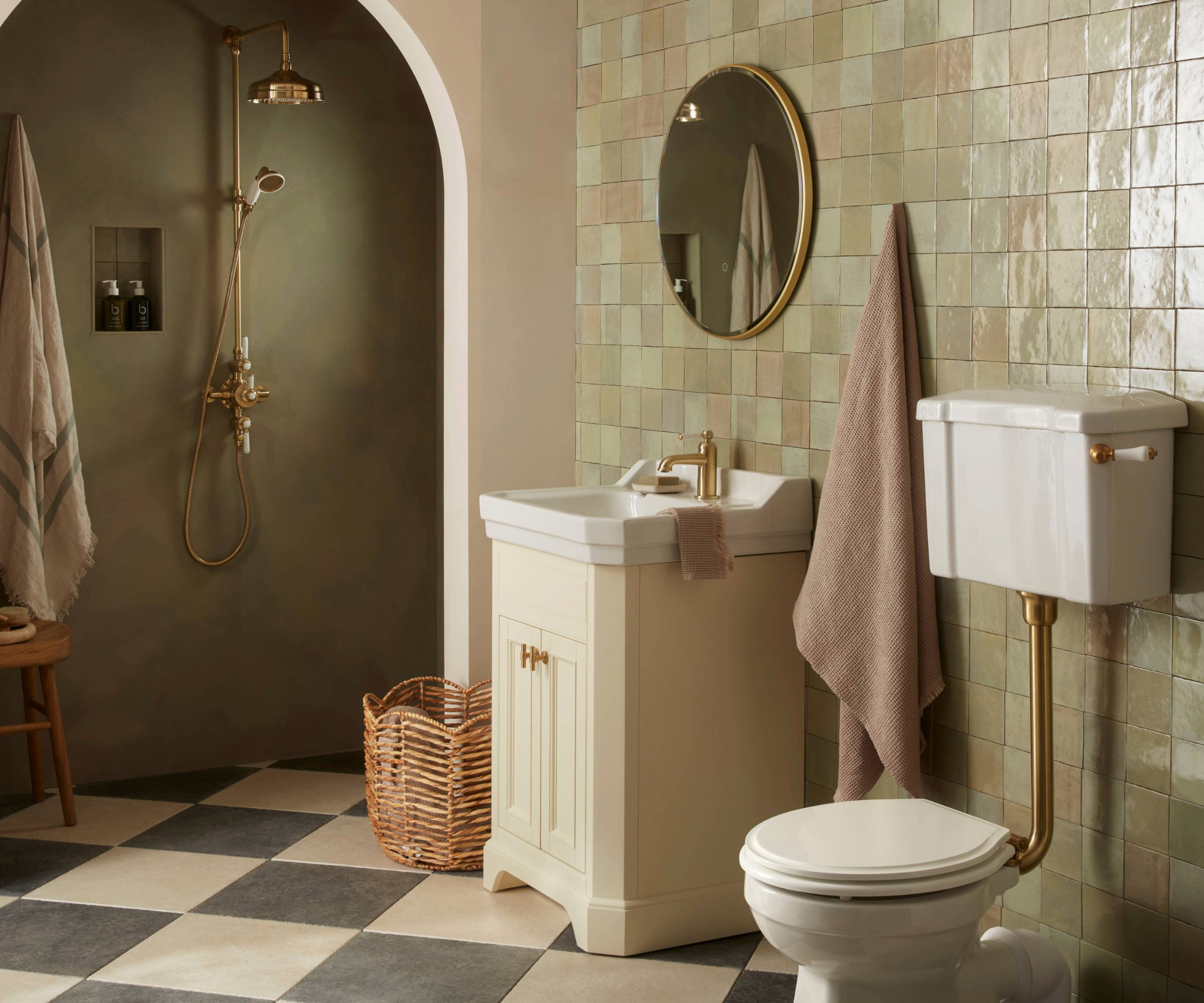 Bathroom with sage green tiles to the left and an arched shower nook which is painted in a darker green with a gold shower