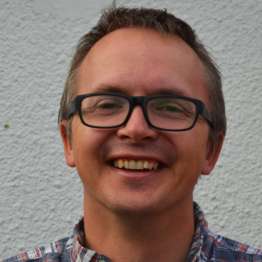 male with short brown hair and black glasses